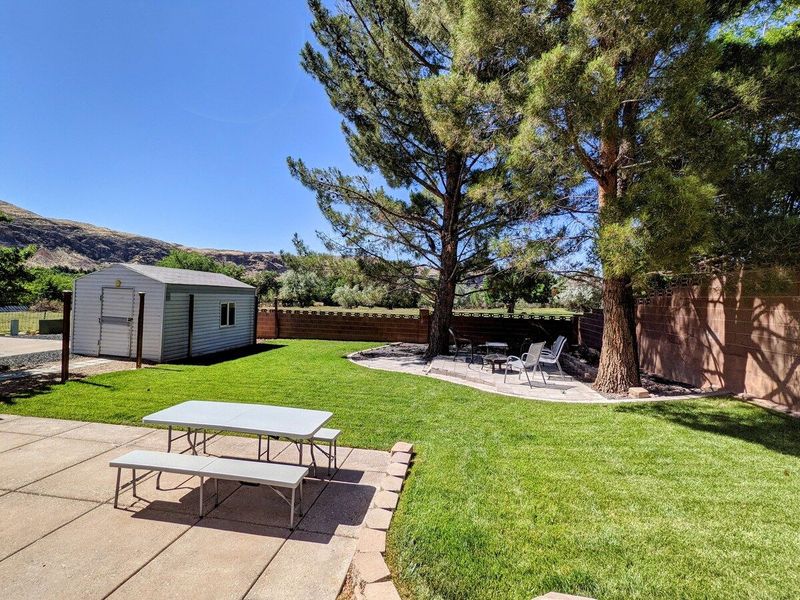 Backyard with picnic table, grassy area, and sitting area with firepit