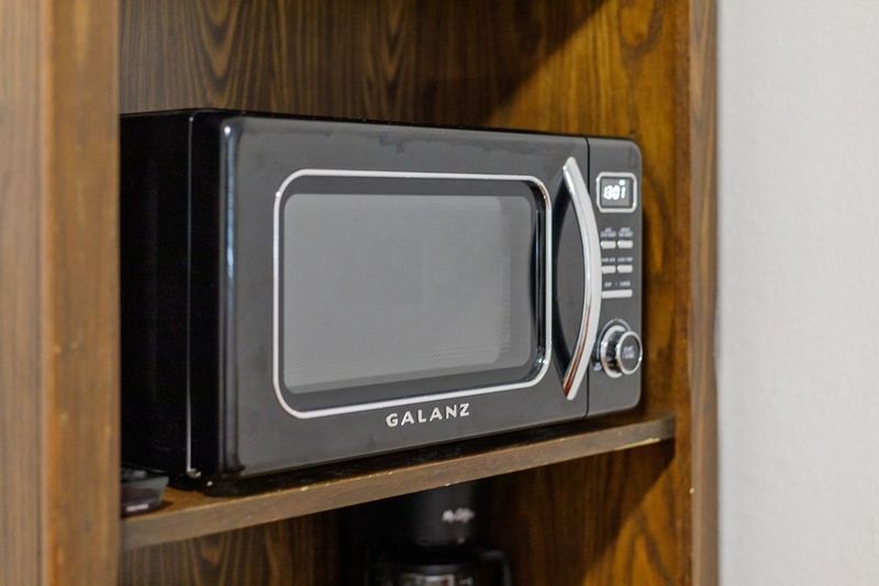 Mini kitchenette with microwave, fridge, coffee maker & toaster.