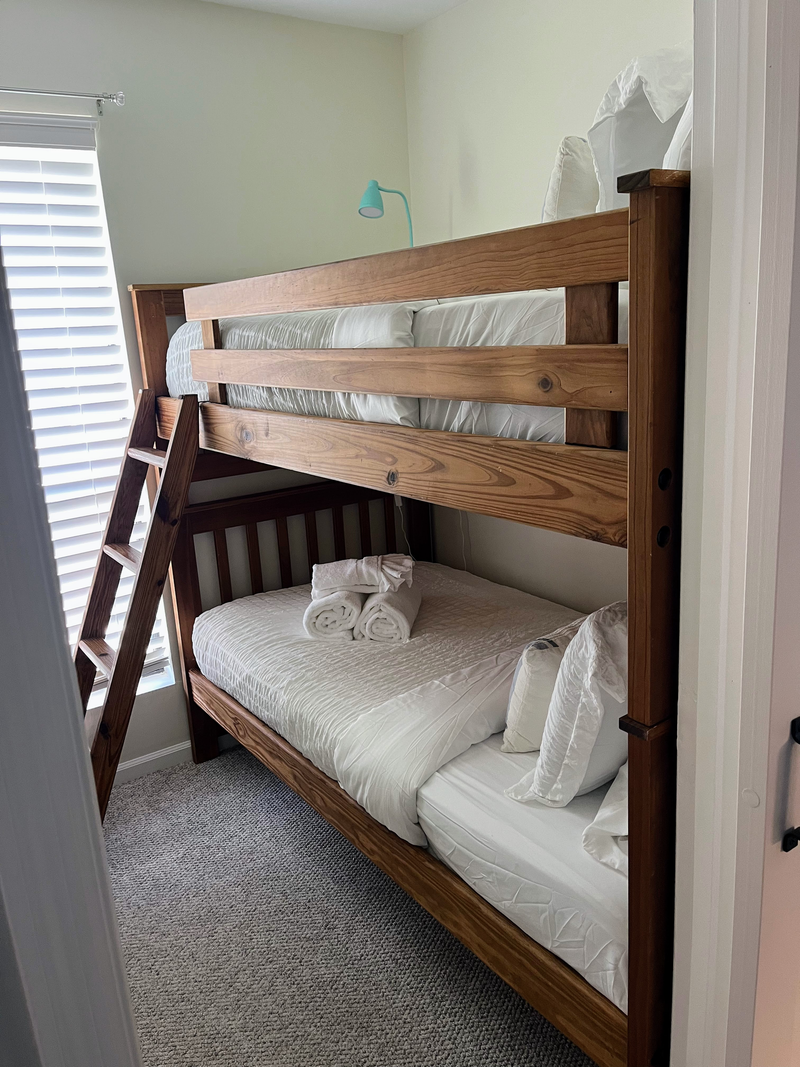 Cozy bunk room with natural light and sturdy wood beds for extra guests