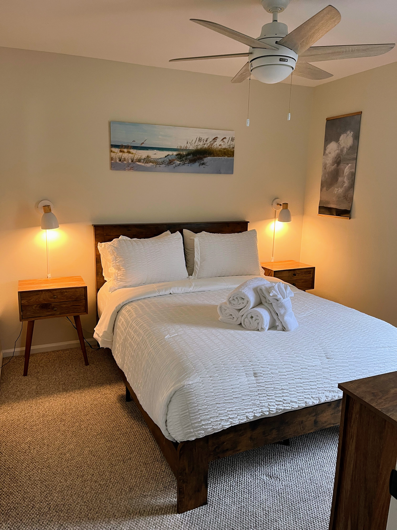 Cozy coastal bedroom with queen bed, reading lights, and warm modern style