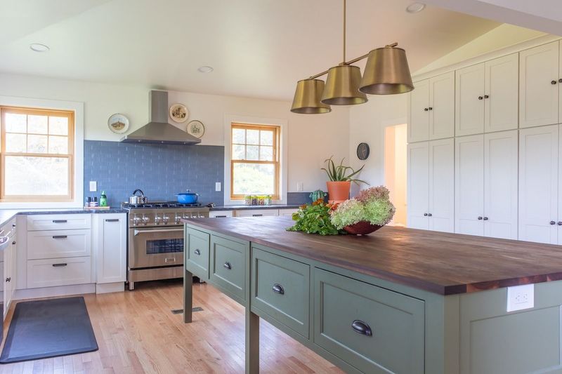 Chef's Kitchen with a large 10-foot island. Island has an oiled walnut top with green accent cabinetry below. 