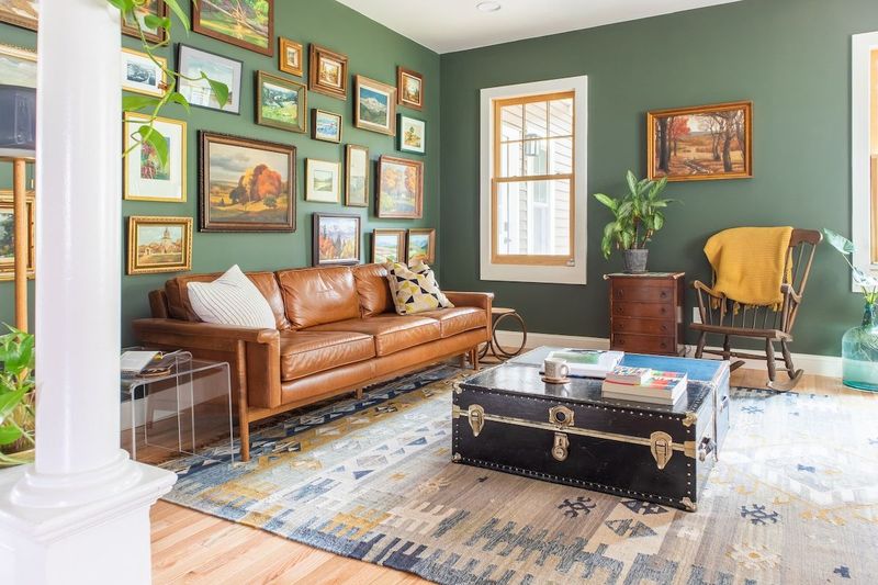 Formal living room has a leather sofa, comfortable arm chairs surrounded by antique landscape oil paintings.