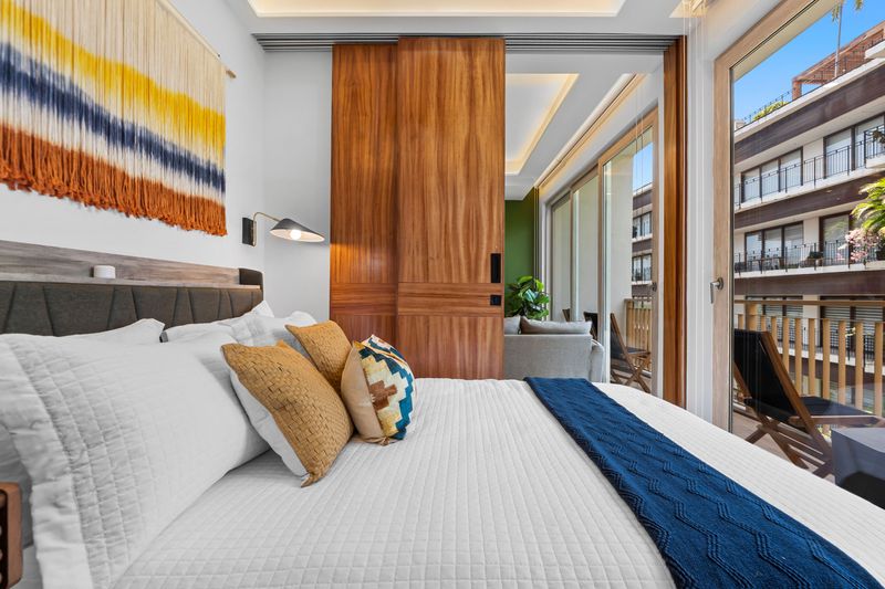 Bright modern bedroom with balcony access and warm designer touches