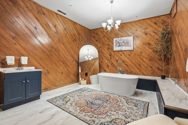 Spacious ensuite bathroom in the downstairs main suite featuring a large vanity, soaking tub, and warm wood accents. Thoughtfully designed with plenty of space and natural character, creating a relaxing place to unwind.
