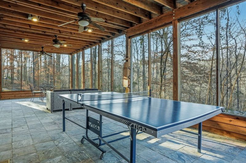 Spacious fully screened-in downstairs patio designed for gathering and connection. With comfortable seating, dining space, and a ping pong table, it’s the perfect spot to hang out, play games, and enjoy time together surrounded by nature.