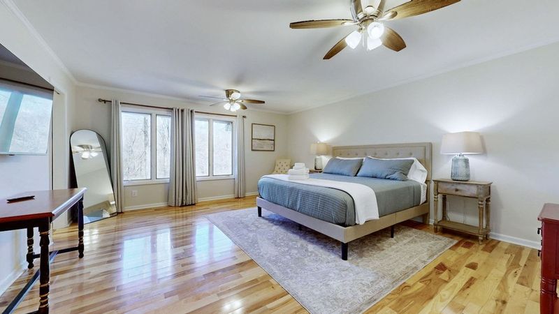 Spacious upstairs bedroom with a king bed, abundant natural light, and a private ensuite bathroom. Features a TV and cozy seating area.