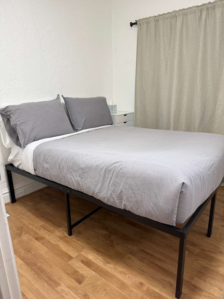 Clean, cozy bedroom with neutral decor and warm wood flooring