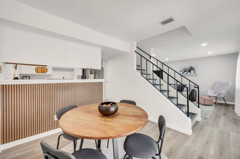 Bright open dining space with stylish staircase and cozy lounge area