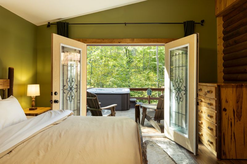 Cozy cabin bedroom with private deck and forest-view hot tub