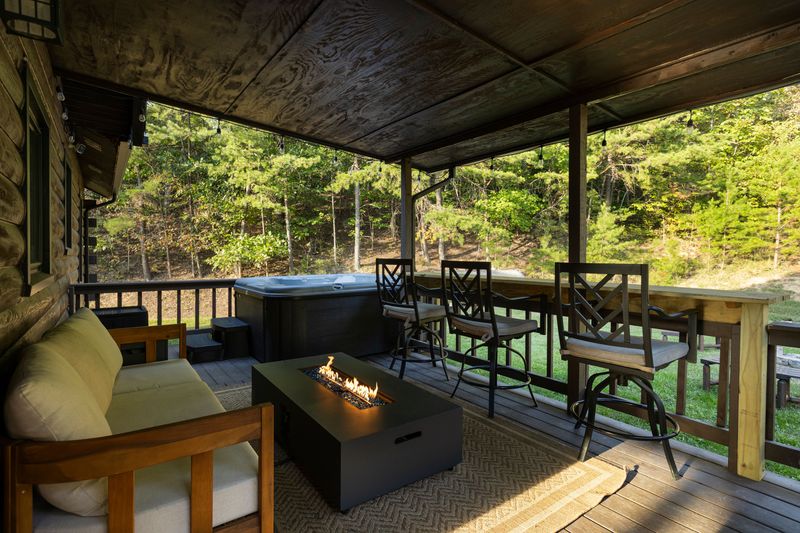 Private covered deck with hot tub, fire table, and peaceful forest views