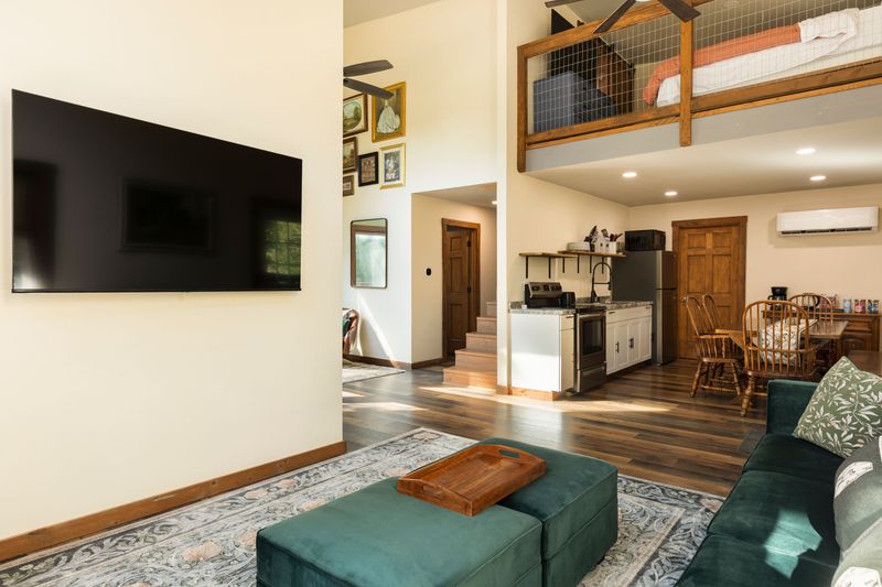 Bright open-concept living space with loft, full kitchen, and large TV